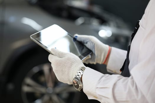 Male master locksmith holds tablet and performs car diagnostics