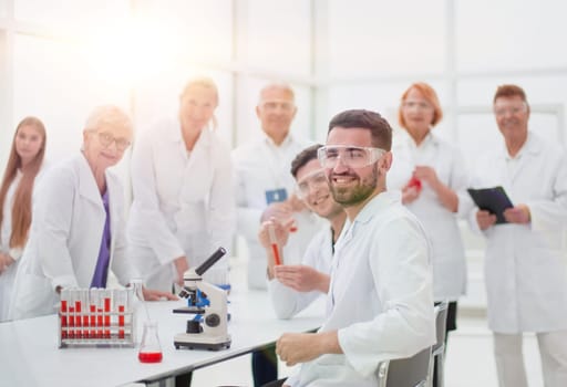 smiling scientist sitting at a laboratory table .