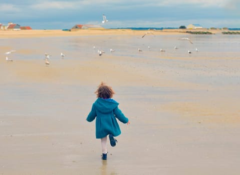 Girl in a green coat and seagulls