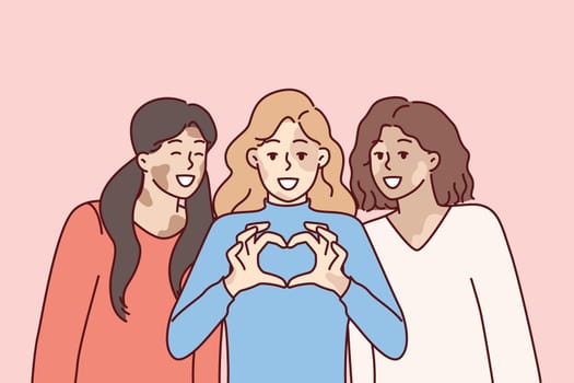 Three women with vitiligo syndrome are smiling demonstrating heart gesture as sign of self-love