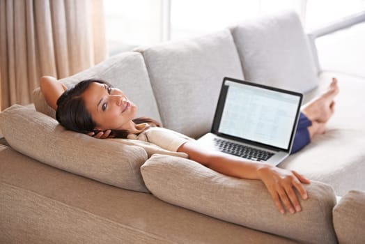 Spread out on the couch. Portrait of an attractive young woman relaxing on the couch with her laptop.