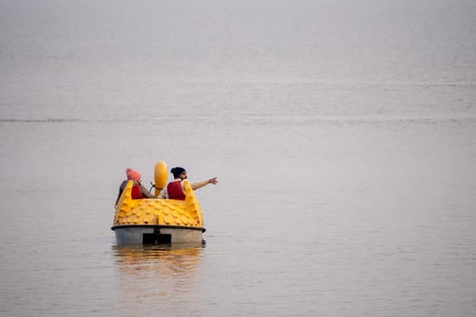 couple enjoying a pedal boat decorated beautifully on the landmark sukhna lake in chandigarh with more boats in the distance showing this popular tourist spot