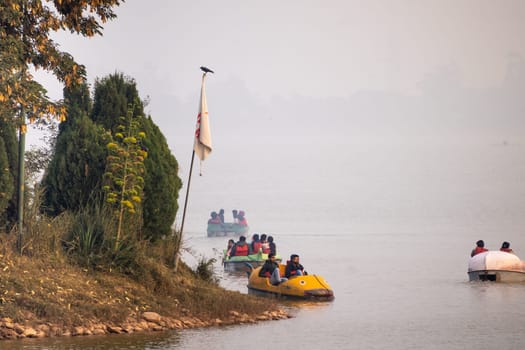 couple enjoying a pedal boat decorated beautifully on the landmark sukhna lake in chandigarh with more boats in the distance showing this popular tourist spot