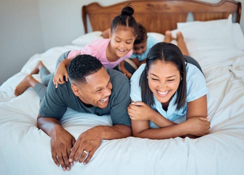 Happy family with kids, smile and lying on bed in home, mother and father with children together in Mexico. Love, fun and family time for dad, mom and babies playing in family bedroom on weekend