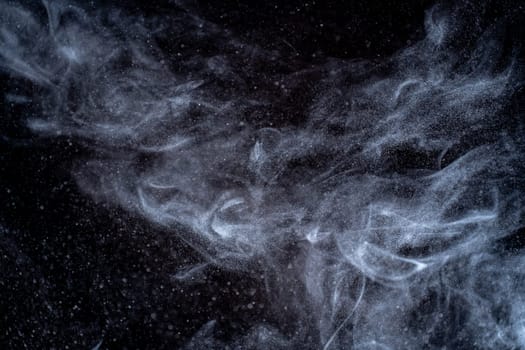 Dust particles cloud generating abstract shape on black background with copy space for text.