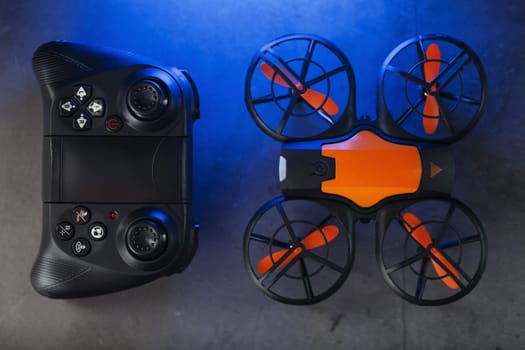 Gaming orange mini drone on a dark background with a joystick control