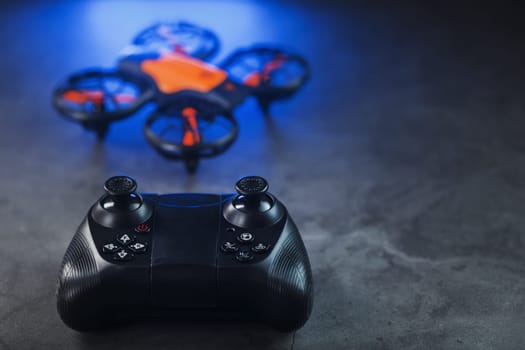 Gaming orange mini drone on a dark background with a joystick control