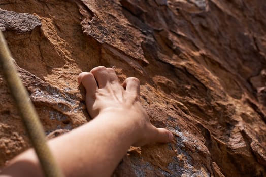 Get a grip. Closeup of a rock climber holding on to a rockface.