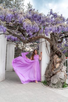 Woman wisteria purple dress. Thoughtful happy mature woman in purple dress surrounded by chinese wisteria
