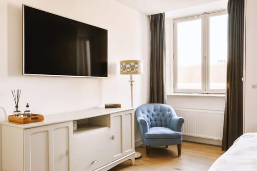 a bedroom with a blue chair and a tv on