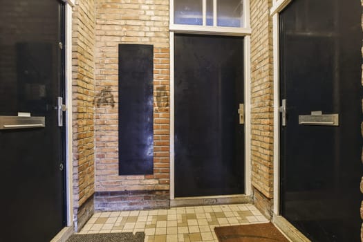 two black doors to a brick building with a door