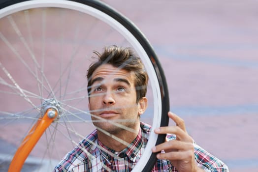 The perfect city transportation. a handsome man inspecting the wheel of his bicycle.