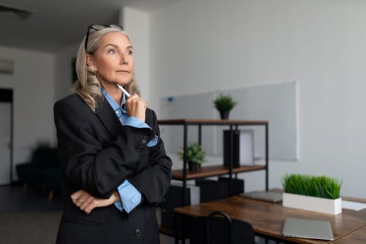 mature adult female economist with gray hair stands in the office building