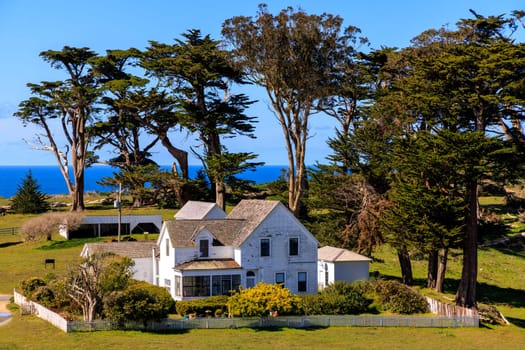 Historic white house and tall trees on rustic ranch in coastal California