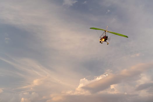 Propeller plane flies in the sunset sky. A small private hang-glider in a cloudy sky.