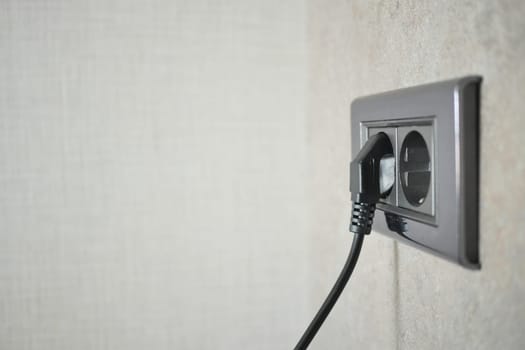 black color power cord cable plugged into wall