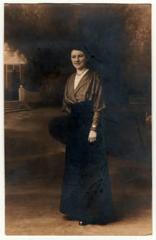 Vintage photo shows woman poses in a photography studio. Photo with dark sepia tint. Black white studio portrait.