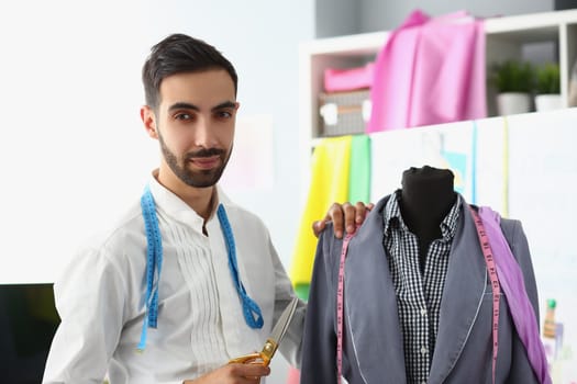 Male stylist designer holding scissors next to mannequin