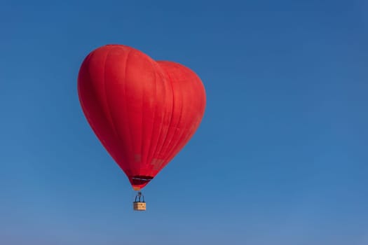 Hot air balloon in the shape of a heart in the blue sky. Honeymoon concept for newlyweds