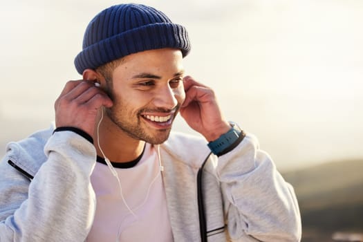 Man with earphones, listening to music and smile outdoor with runner, fitness and motivation with radio streaming. Podcast, technology and exercise at sunset, happy male and running, audio and sport.