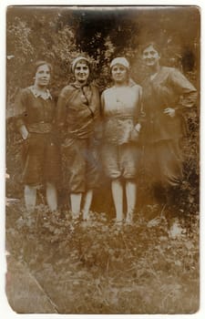 Vintage photo shows young rural women pose in nature. Black white antique photography.