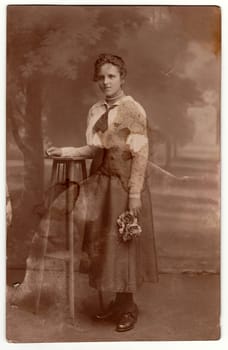 Vintage photo shows a young woman holds roses. Studio photography with sepia effect.