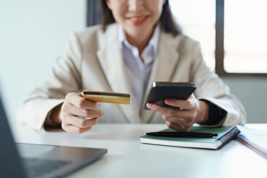 Portrait of young Asian woman using credit card and phone for online shopping