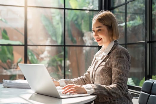 Portrait of young business woman using laptop and documents on the table at office