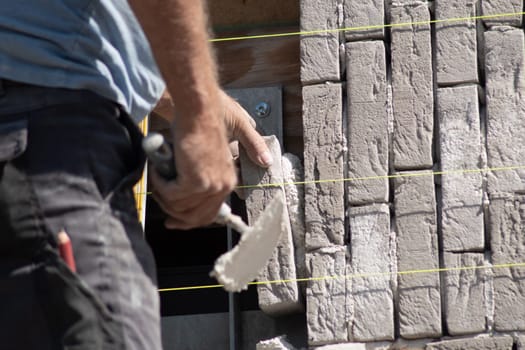 close-up Builder glues a gray brick with cement to the masonry on the wall