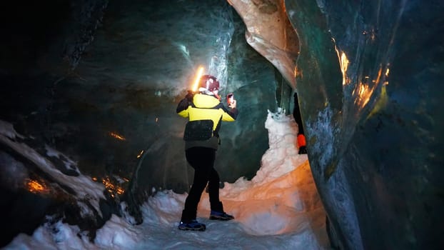 A girl with a neon lamp stands in an ice cave