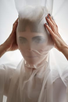 Woman portrait pulling fabric over her face hiding face mask