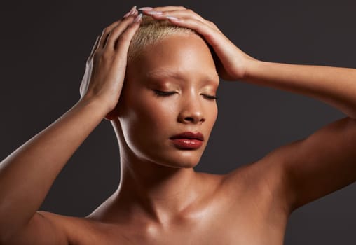 Skincare, makeup and black woman with hands on head in dark studio, platinum hair isolated on grey background. Art aesthetic, cosmetics and African beauty model and luxury spa facial for bronze skin.