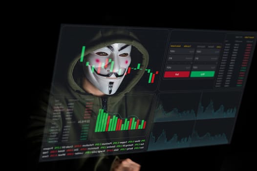 June 5, 2022 Novosibirsk, Russia: Anonymous in a hood is typing on a laptop in the dark in red light. HUD menu. Stock charts. broker terminal.