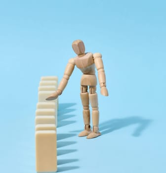 Wooden toy mannequin keeps dominoes from falling, risk prevention concept
