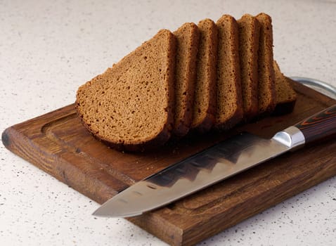 Triangular rye piece of bread on a wooden cutting board