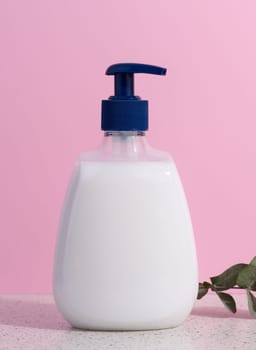White plastic container with a pump for liquid products on a pink background. Container for cosmetics, soap, cream