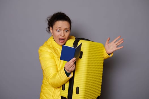 Female tourist passenger with yellow suitcase and passport, expressing disappointment of problems with visa or documents