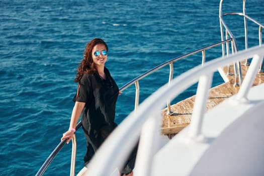Mature woman standing on the yacht and enjoying her vacation on the sea