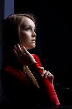Portrait of beautiful young woman in red dress in dark nightclub