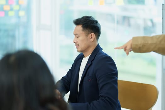 An image of an Asian male employee looking worried and sad about being scolded by his boss for failing to meet sales targets, concept of disappointment and failure in his career