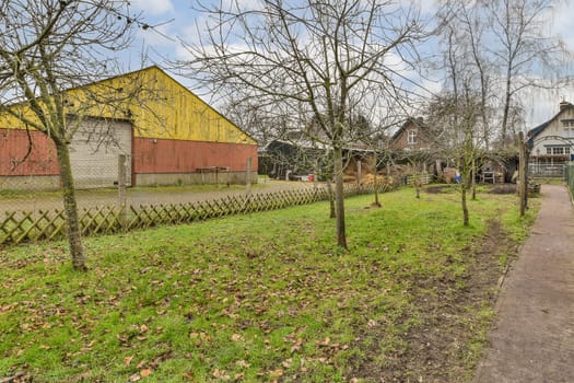 a yard with trees and a yellow and red barn