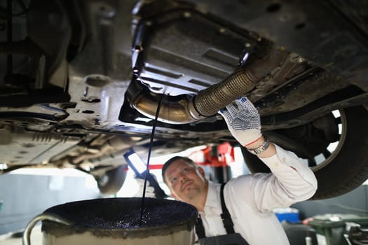 Auto mechanic repairman inspecting car engine in garage of service station