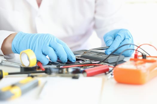 Technician repairs motherboard of smartphone in laboratory