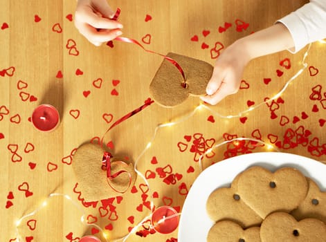Childs hands making a garland from the selfmade baked heart cookies.