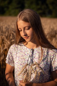 Portrait of a girl with some spikelets in the field of ripe grain