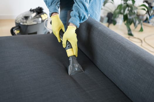 Man cleaning couch with washing vacuum cleaner, closeup