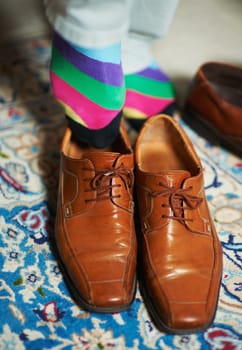 Socks and shoes that speak louder than words. a man putting on colourful socks and loafers.