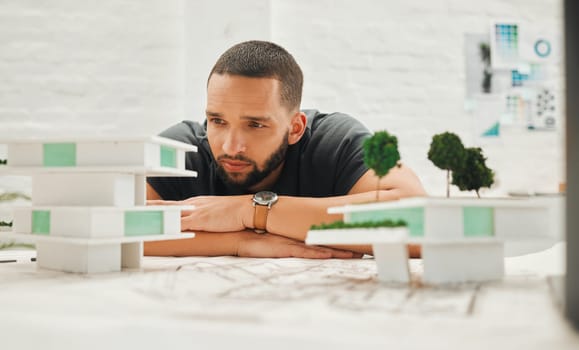 Focused architect looking at building model. Young businessman thinking about a building model. Handsome engineer working on a 3D building model. Engineer working on a 3D model