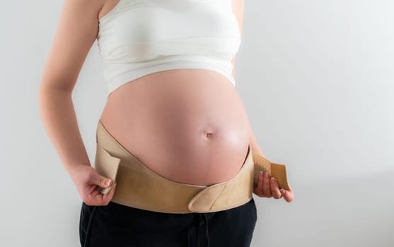 Pregnant woman adjusts additional fasteners on the orthopedic belt to support the belly