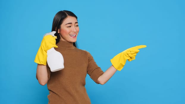 Cleaning woman pointing and showing cleaning product or isolated text